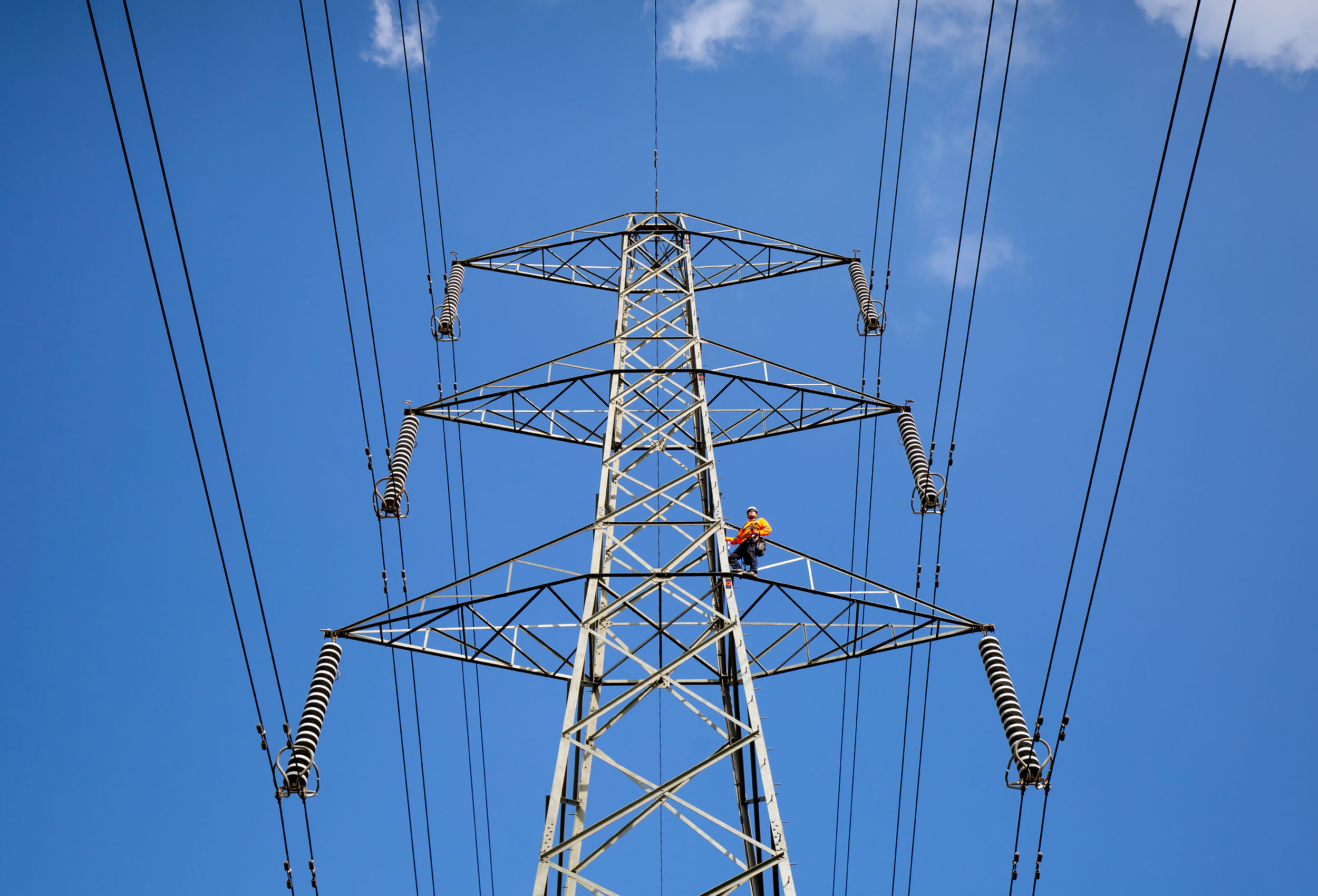 Commercial photography of National Grid lineworker climbing an OHL tower