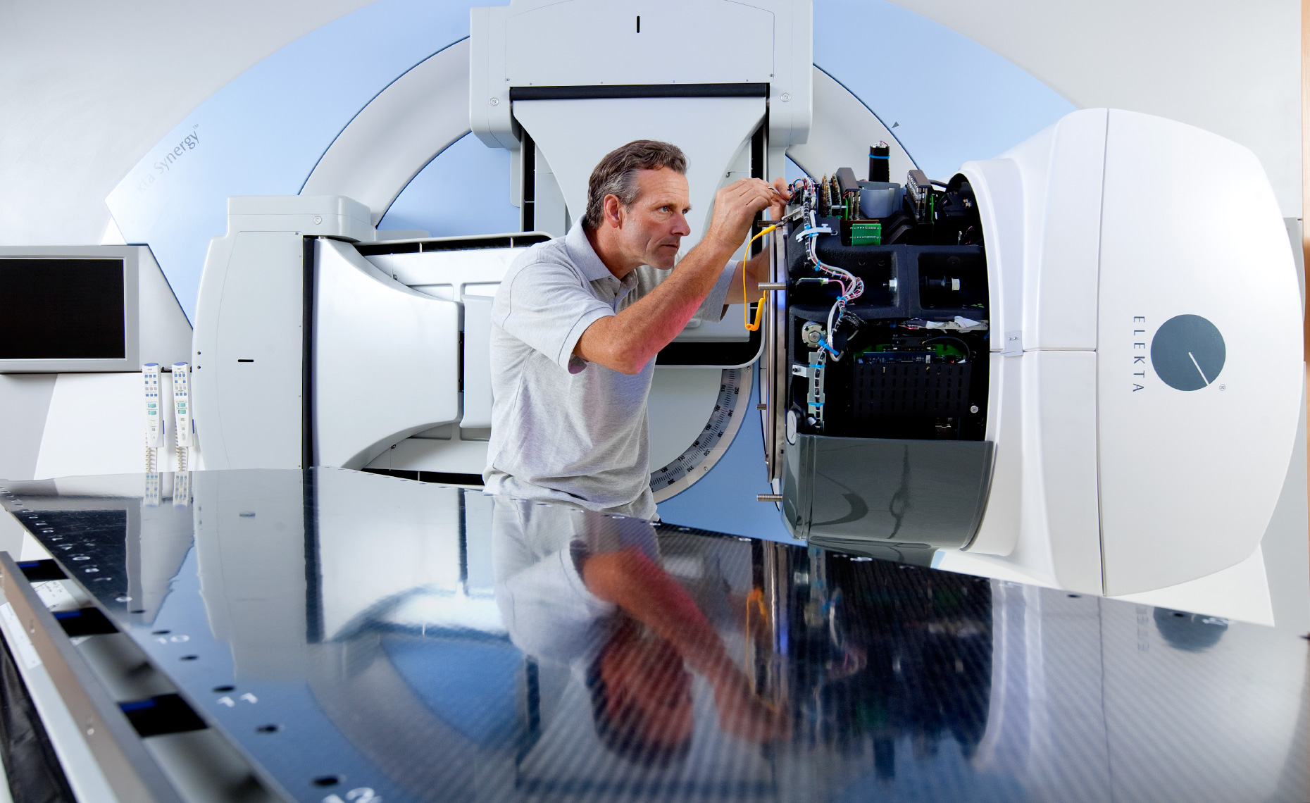 Editorial commercial photography of engineer working on radiotherapy machine in a hospital.