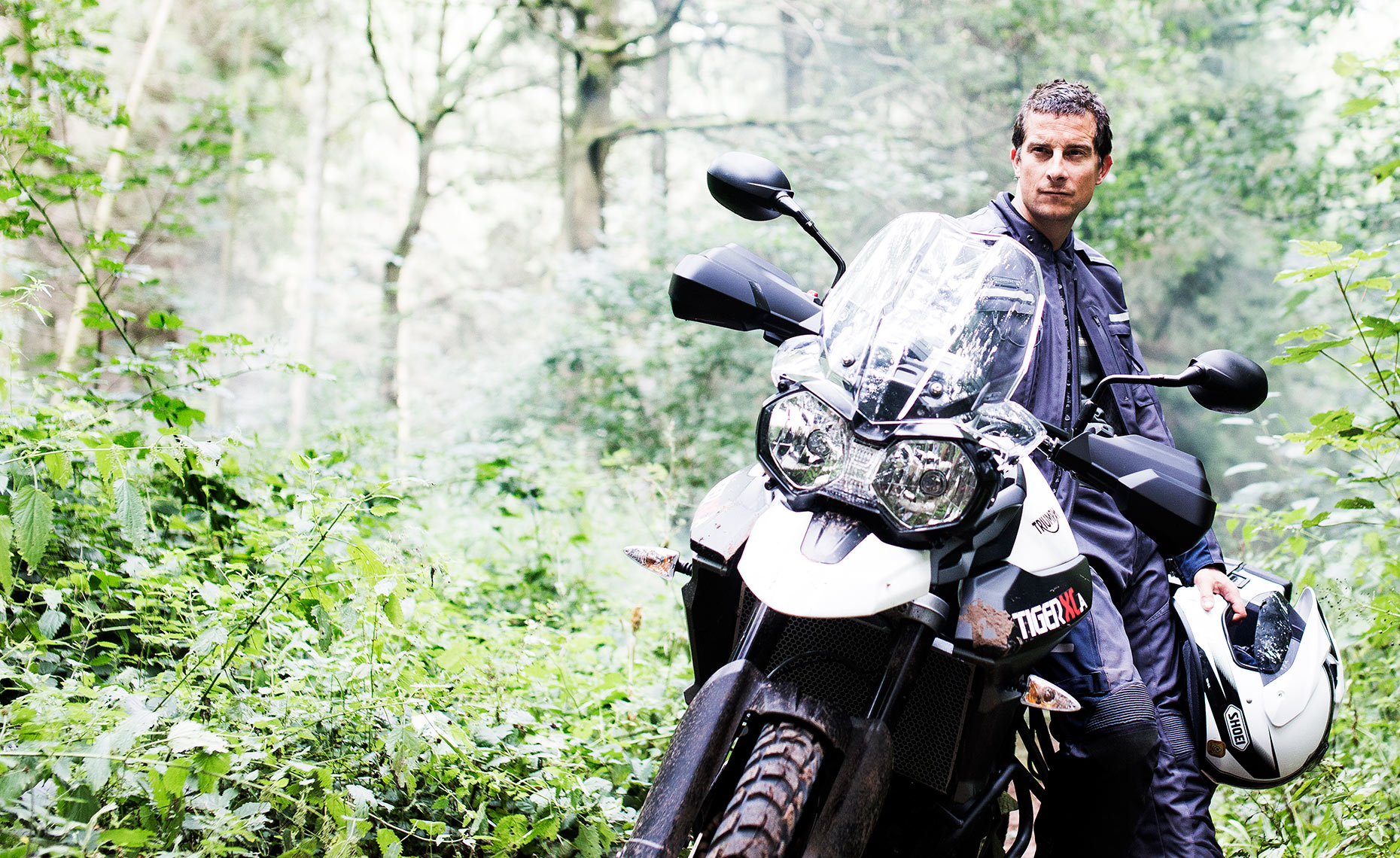 Environmental portrait of survival expert Bear Grylls test riding a Triumph motorbike.