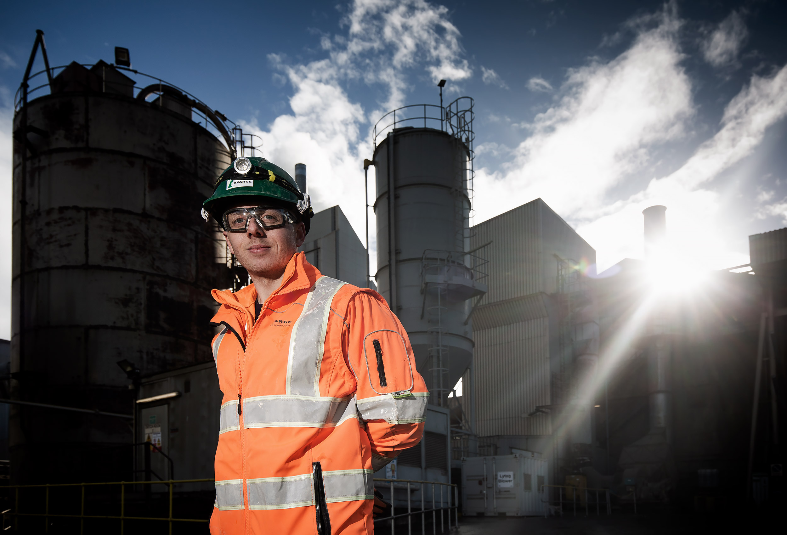 Commercial photography of an engineer wearing PPE in front of a cement plant.