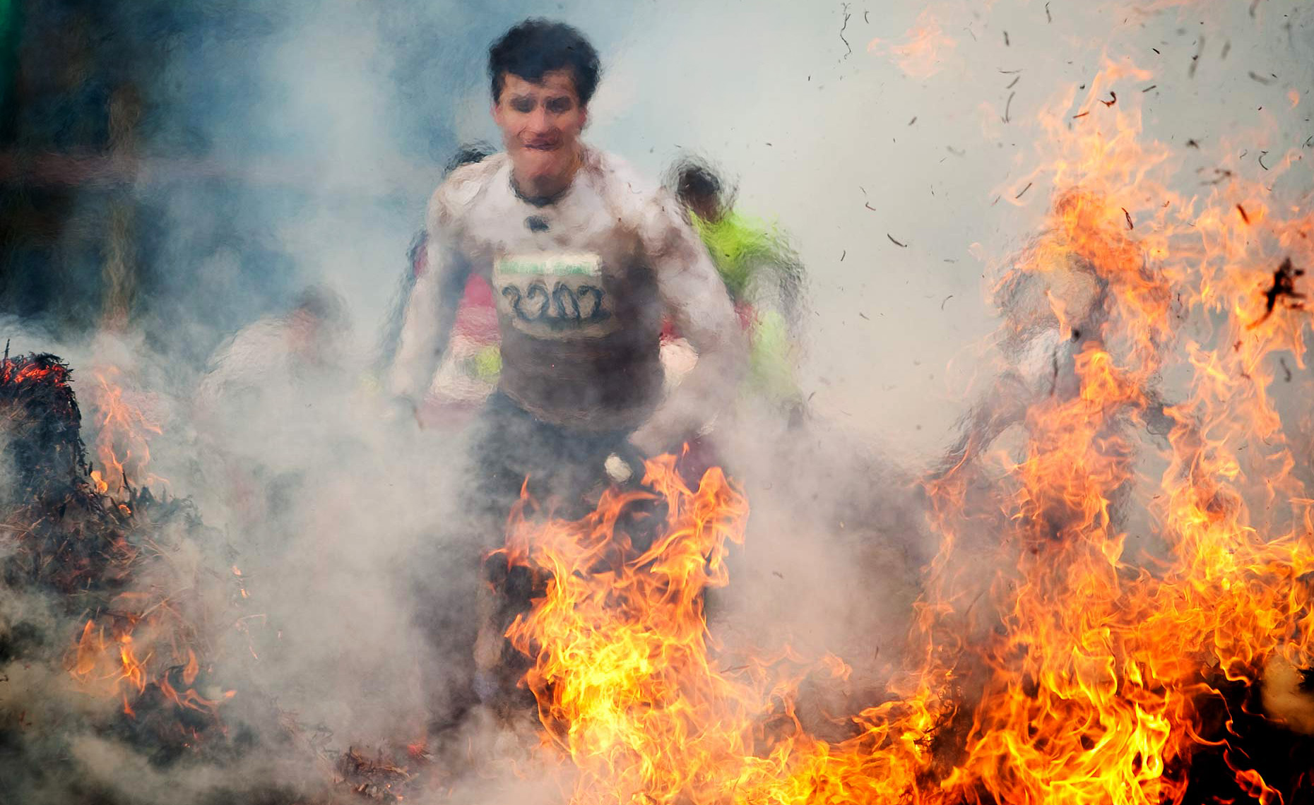 Editorial photography of competitors running through flames during Tough Guy. 