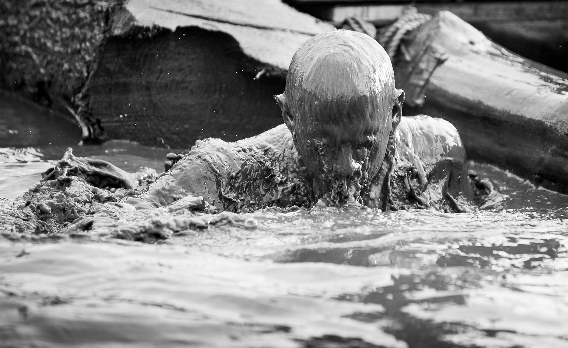 Editorial photography of a competitor emerging from the water during Tough Guy. 