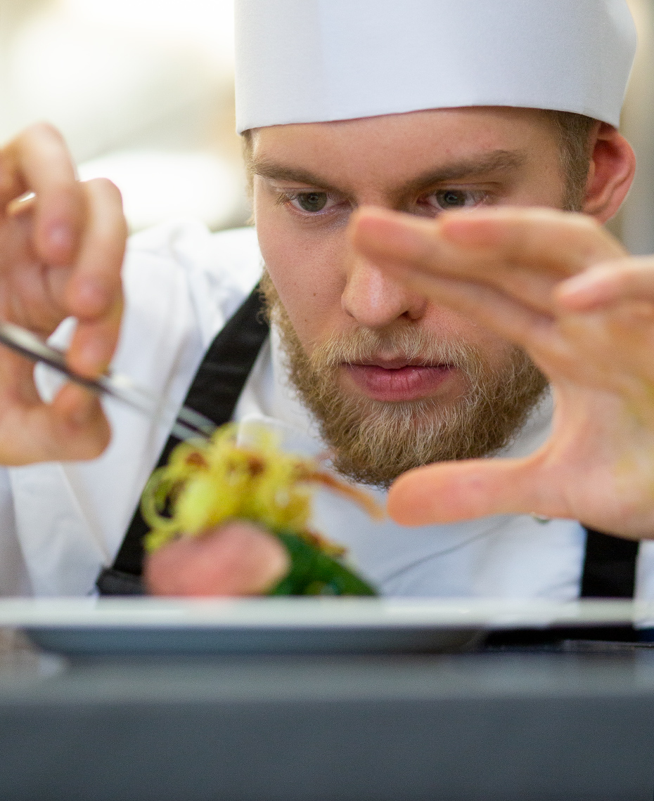 Editorial portrait of a chef putting the final touches to a dish.